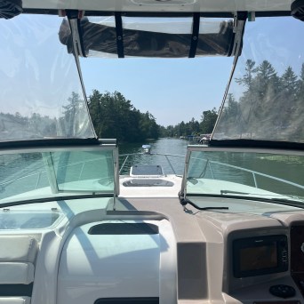 View from a boat cockpit overlooking a calm river and trees.