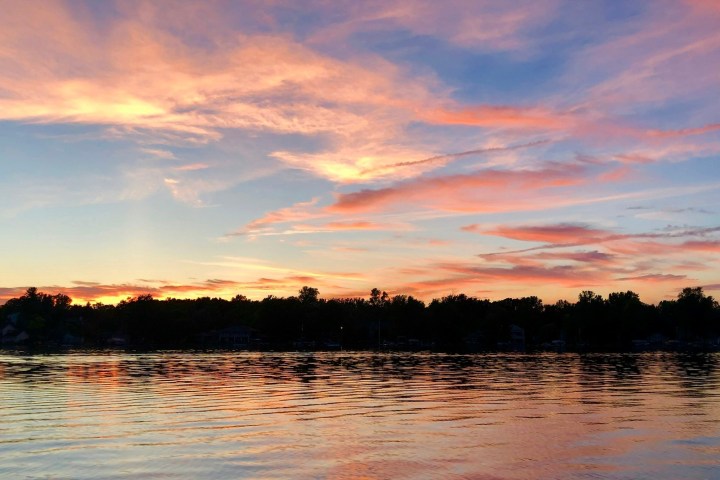 Sunset over a lake with colorful pink and orange clouds.