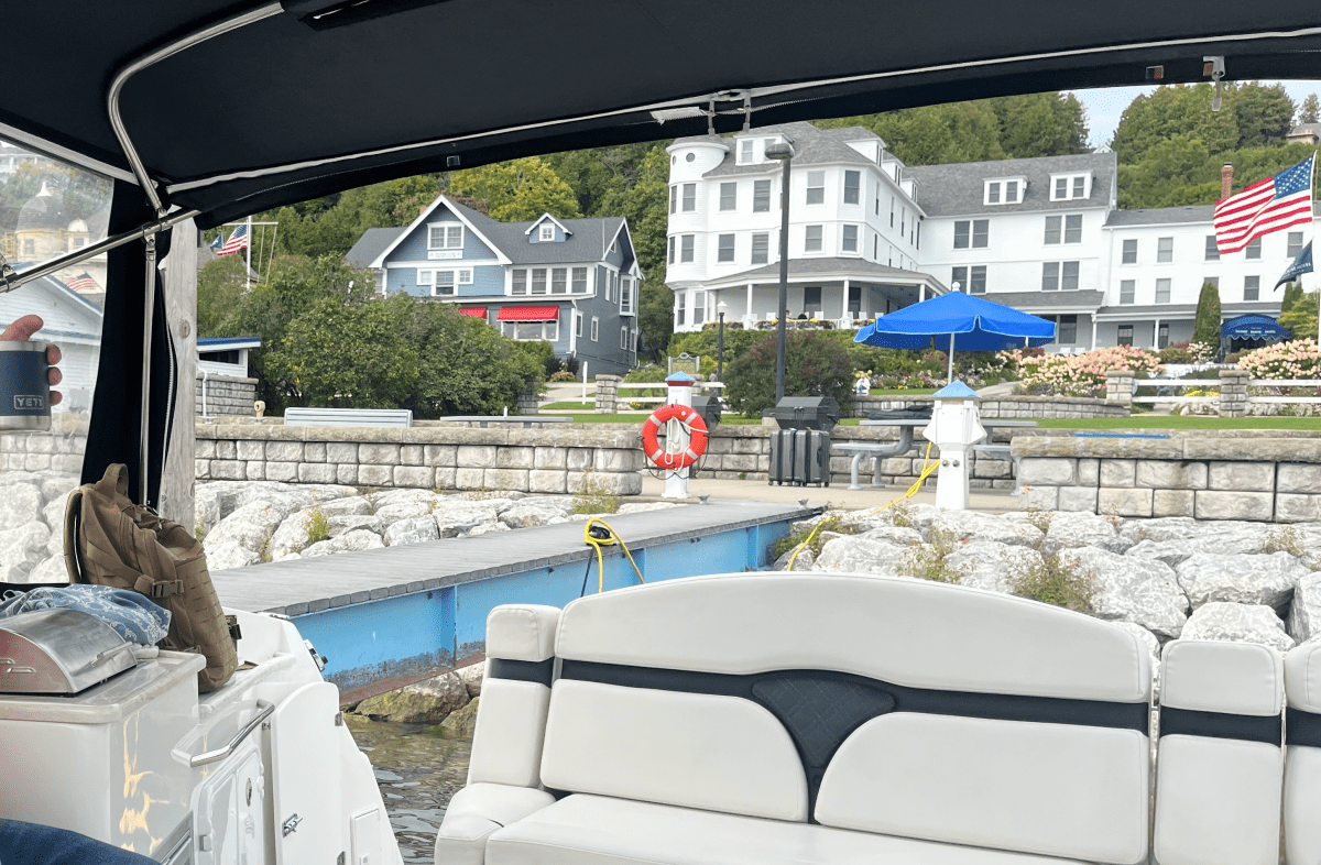 View from boat towards a dock with buildings, American flag, and umbrellas.
