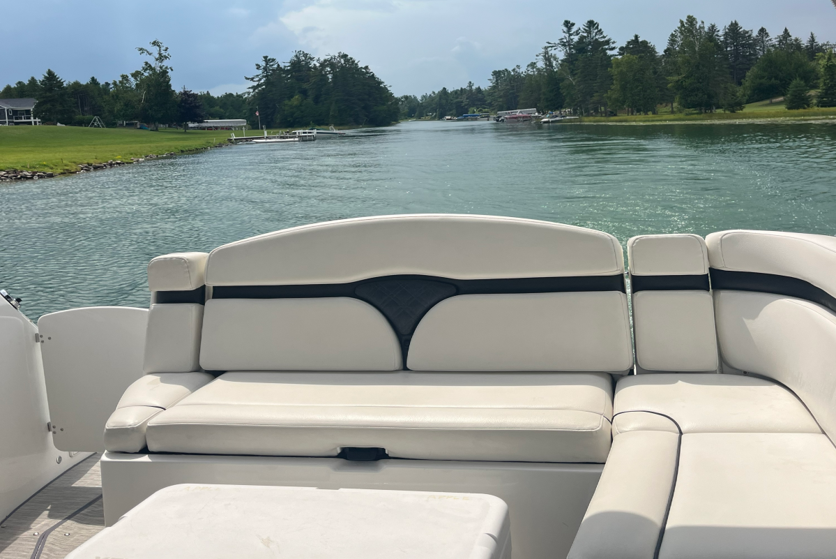 View from a boat with white seats, facing a lake and tree-lined shore.