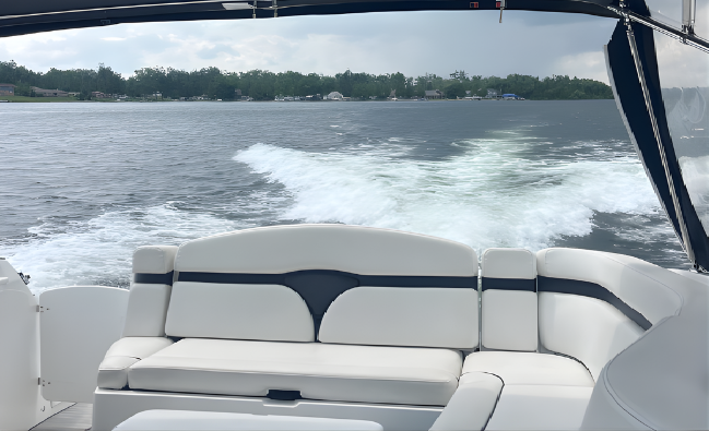 View from boat's seating area looking at water wake on a lake with cloudy sky.