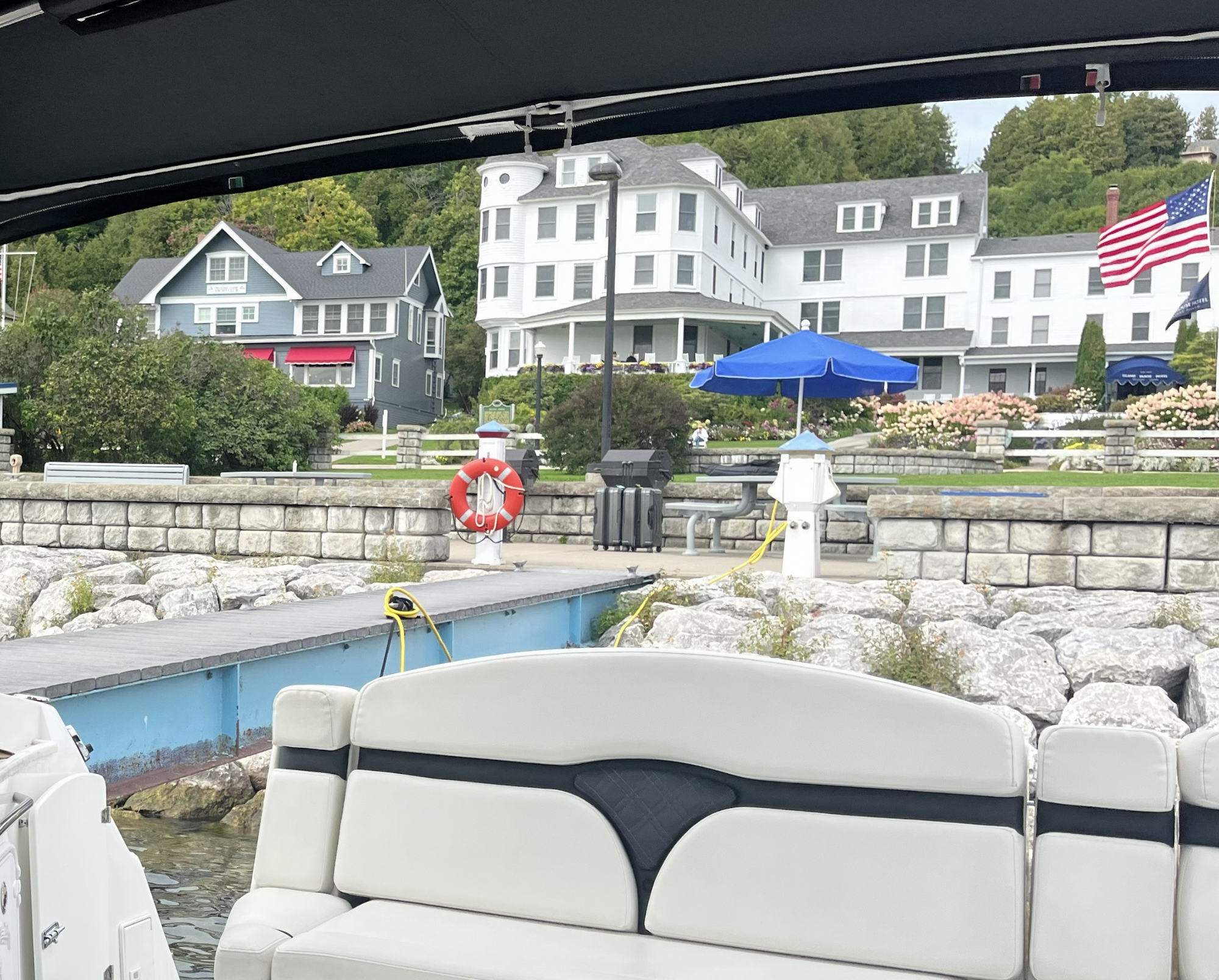 View of waterside with white buildings and American flag from a boat with seating.